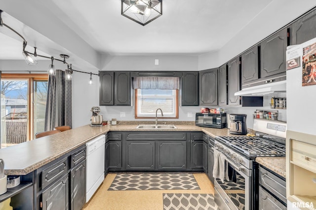 kitchen featuring a wealth of natural light, kitchen peninsula, sink, and white appliances