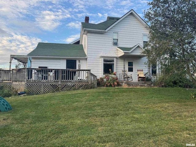 rear view of house with a deck and a yard