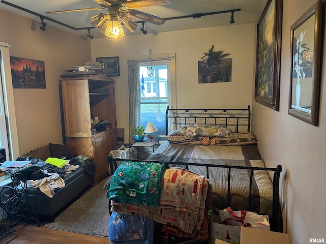 bedroom with ceiling fan, hardwood / wood-style flooring, and track lighting