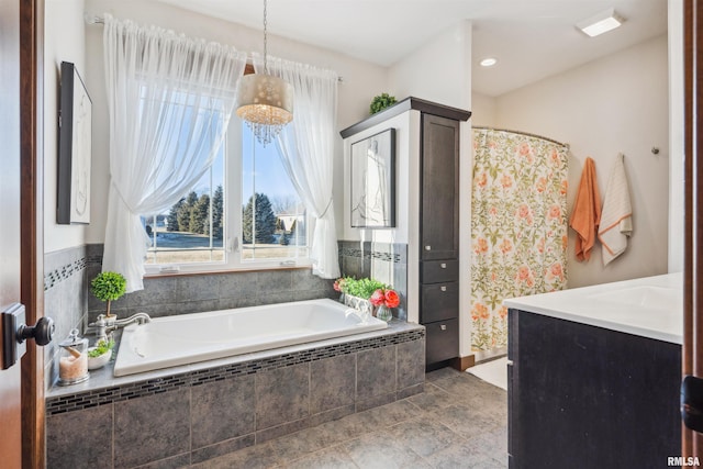 bathroom featuring a relaxing tiled tub and vanity