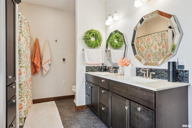 bathroom with toilet, vanity, and backsplash