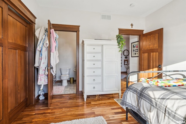 bedroom with ensuite bathroom and hardwood / wood-style flooring