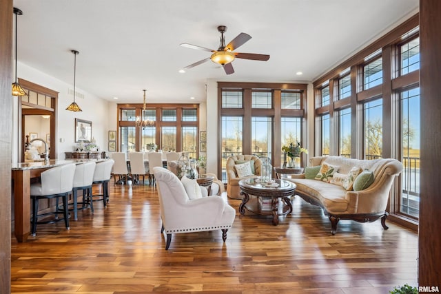 living room featuring ceiling fan with notable chandelier, dark hardwood / wood-style floors, and sink