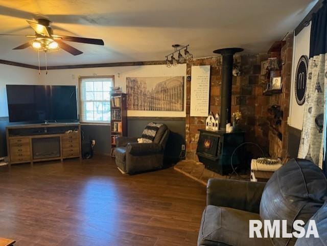 living room with ceiling fan, dark hardwood / wood-style floors, a wood stove, and ornamental molding