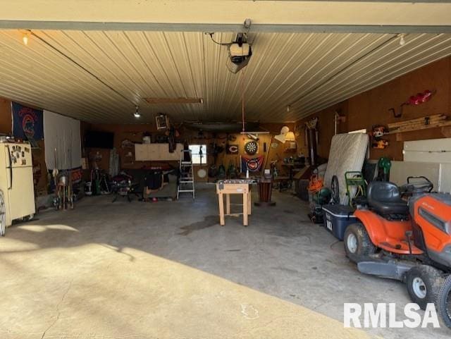 garage with white fridge, a garage door opener, and a workshop area