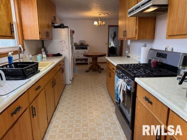 kitchen with decorative light fixtures, white fridge, an inviting chandelier, sink, and stainless steel gas range oven