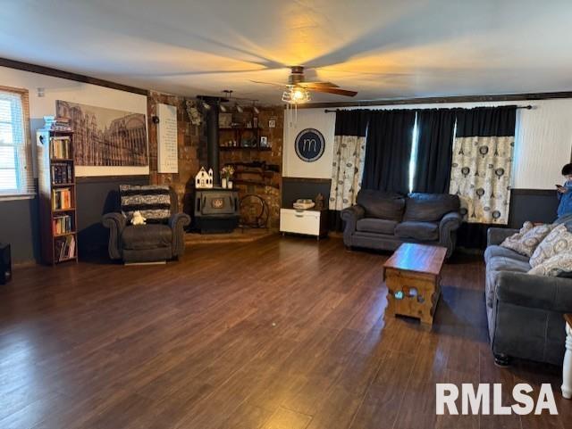 living room featuring ceiling fan, dark hardwood / wood-style floors, and a wood stove