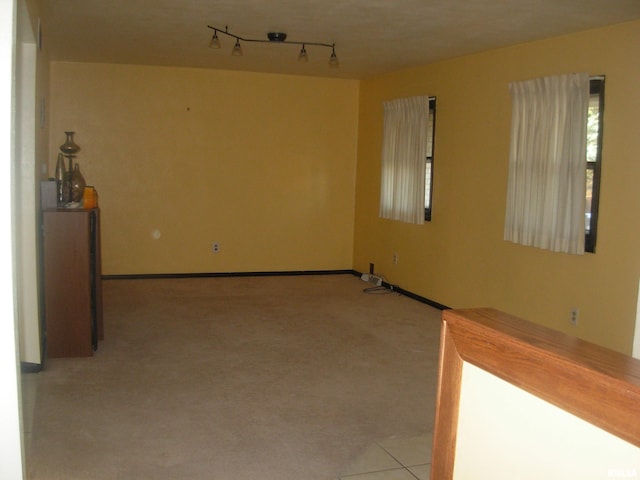 carpeted empty room featuring rail lighting