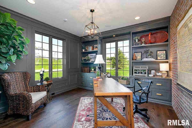 home office with dark hardwood / wood-style floors, a notable chandelier, brick wall, ornamental molding, and built in shelves