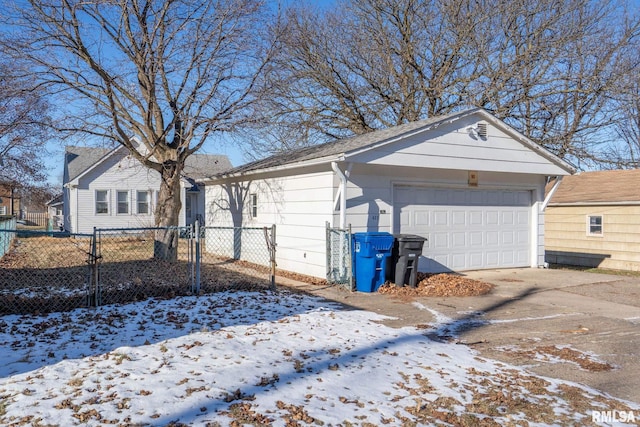 snow covered property with a garage and an outdoor structure