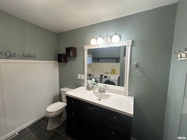 bathroom with toilet, vanity, tile patterned flooring, and washer and dryer