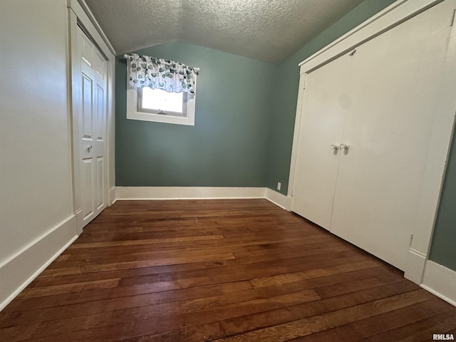 unfurnished bedroom featuring dark wood-type flooring, a textured ceiling, and lofted ceiling