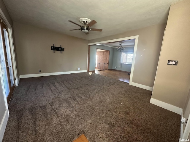 carpeted spare room featuring ceiling fan with notable chandelier