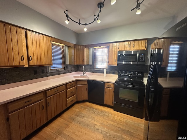 kitchen featuring light hardwood / wood-style floors, sink, black appliances, and tasteful backsplash