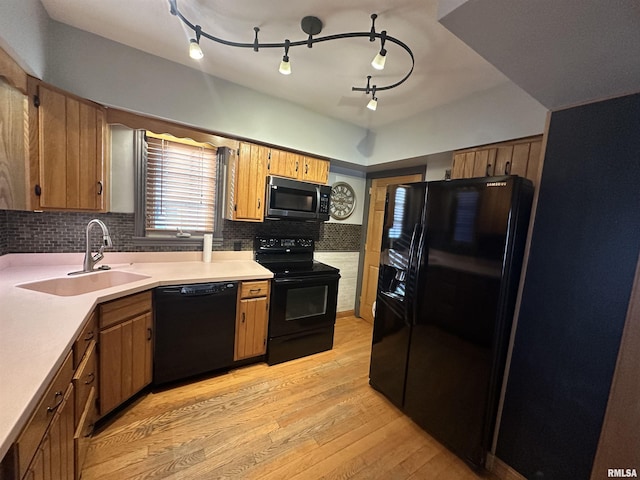 kitchen with black appliances, sink, tasteful backsplash, and light hardwood / wood-style flooring