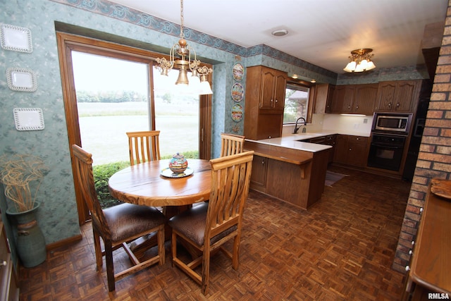 dining space featuring sink, a water view, dark parquet floors, and an inviting chandelier