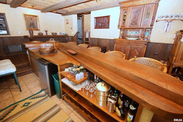 bar featuring wood walls, beam ceiling, sink, wood ceiling, and light tile patterned floors