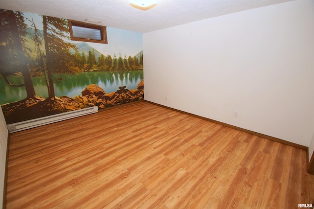 spare room with a baseboard heating unit, a textured ceiling, and light hardwood / wood-style floors