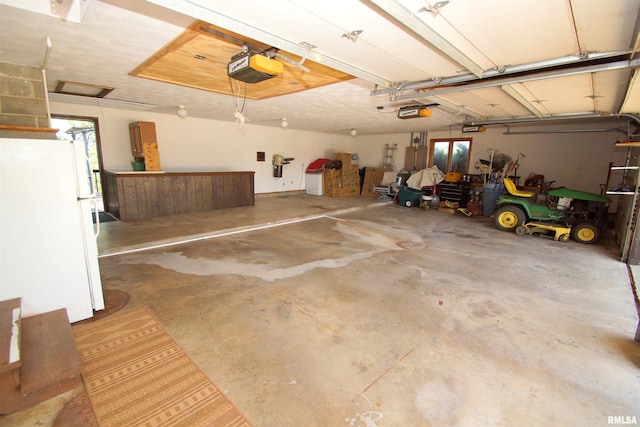 garage with a garage door opener and white refrigerator