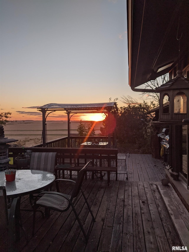 deck at dusk featuring a water view