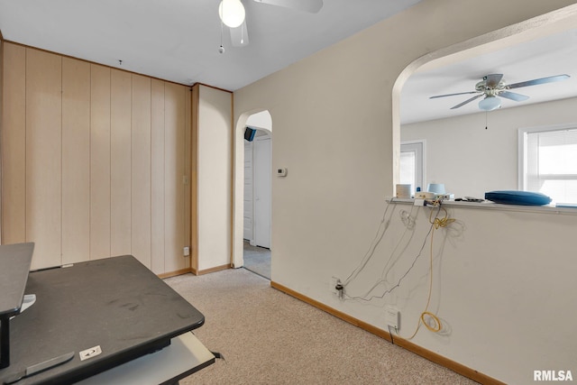 interior space featuring ceiling fan and wood walls