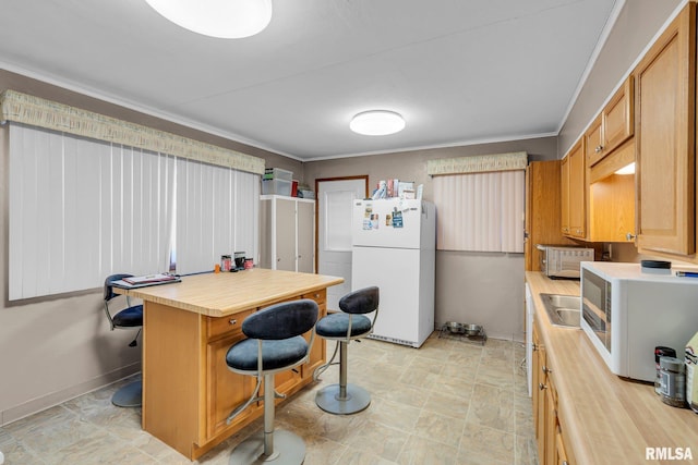 kitchen featuring crown molding, a kitchen bar, sink, and white appliances