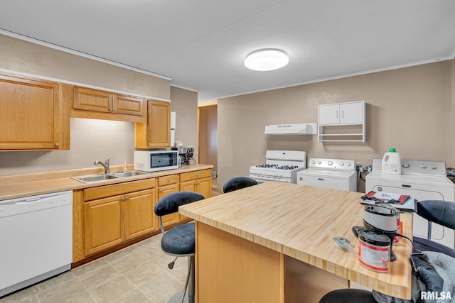 kitchen with sink, white appliances, washing machine and clothes dryer, a kitchen breakfast bar, and butcher block counters