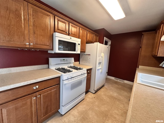 kitchen featuring sink, white appliances, and light tile patterned flooring