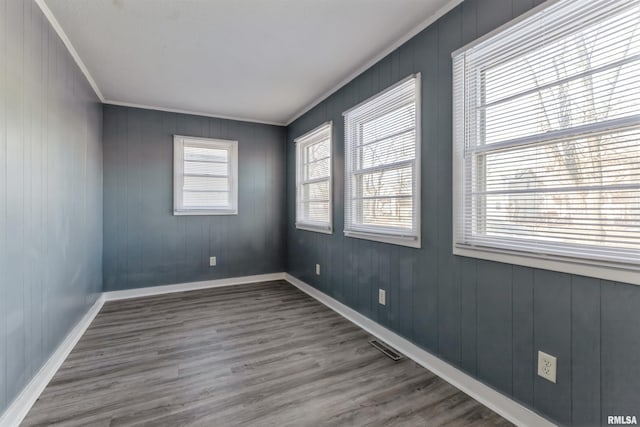 unfurnished room featuring wood-type flooring, a wealth of natural light, and crown molding