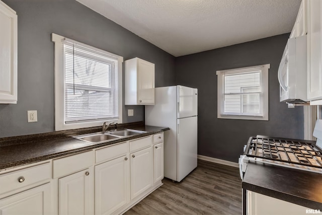 kitchen featuring sink, white cabinetry, white appliances, and a wealth of natural light