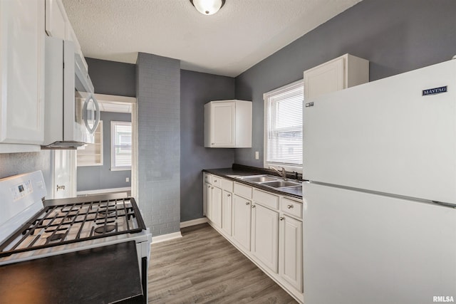 kitchen featuring white appliances, a textured ceiling, white cabinetry, sink, and dark hardwood / wood-style floors