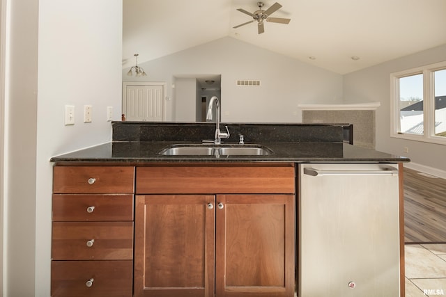 kitchen with sink, vaulted ceiling, dishwasher, ceiling fan, and dark stone counters