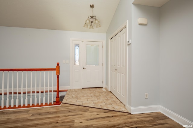 entryway featuring hardwood / wood-style flooring, vaulted ceiling, and an inviting chandelier