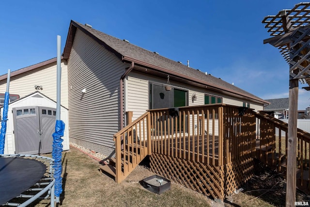 rear view of house with a trampoline, a storage shed, and a deck