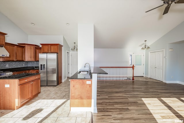 kitchen featuring sink, stainless steel fridge, ceiling fan, tasteful backsplash, and vaulted ceiling