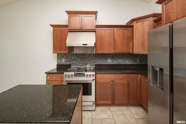 kitchen with light tile patterned floors, appliances with stainless steel finishes, backsplash, exhaust hood, and dark stone counters