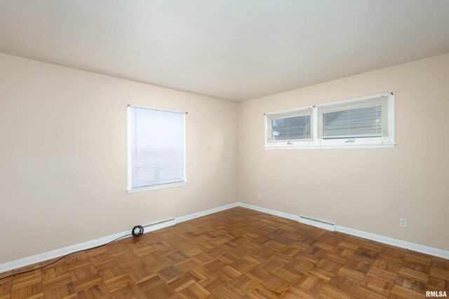 empty room featuring a baseboard heating unit and dark parquet flooring