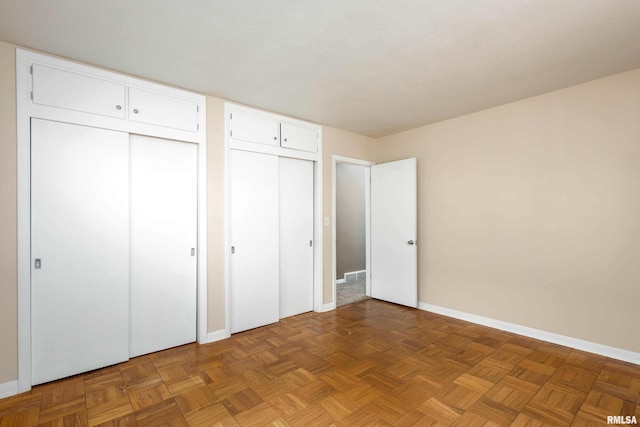 unfurnished bedroom with multiple closets and parquet floors