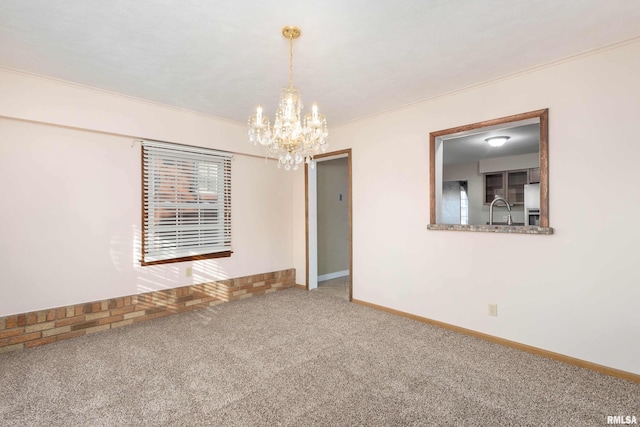 carpeted spare room featuring ornamental molding, a chandelier, and sink