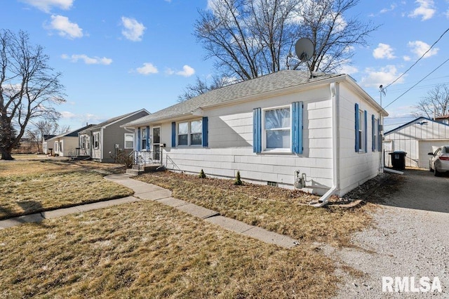 view of front of property with an outbuilding, a front lawn, driveway, and a shingled roof