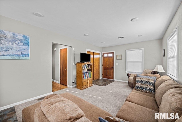 carpeted living area featuring visible vents and baseboards