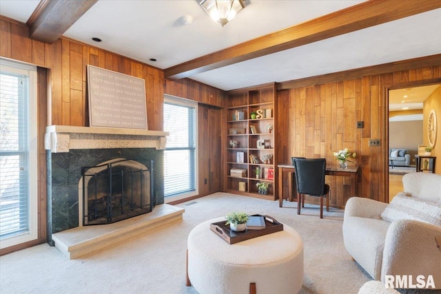 living area with beam ceiling, built in features, wood walls, a premium fireplace, and light colored carpet