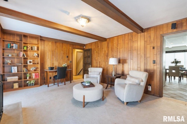 sitting room with beamed ceiling, carpet, and wood walls