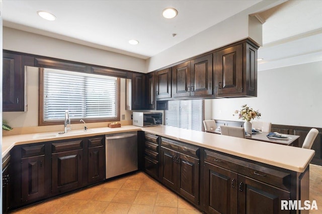 kitchen featuring dark brown cabinetry, appliances with stainless steel finishes, light countertops, and a peninsula