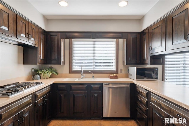 kitchen with dark brown cabinets, appliances with stainless steel finishes, light countertops, and a sink