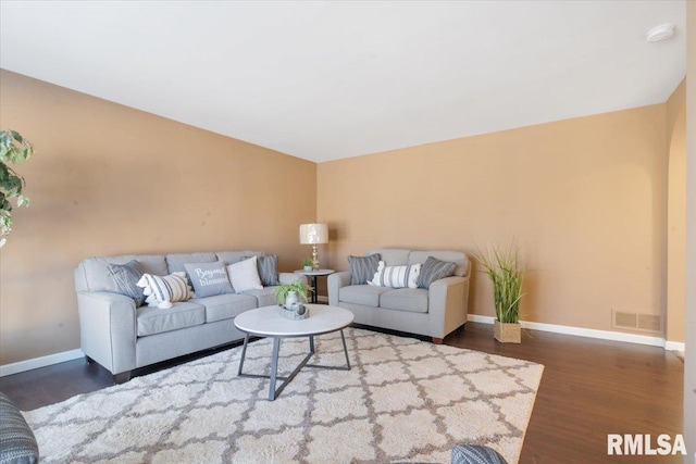 living room featuring wood finished floors, visible vents, and baseboards