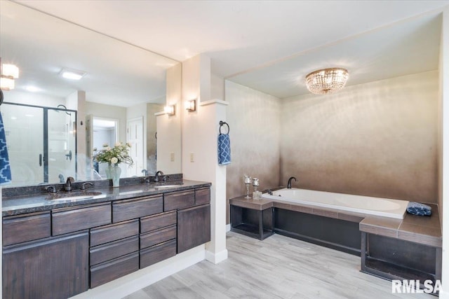 full bath featuring a bath, a stall shower, double vanity, and a sink