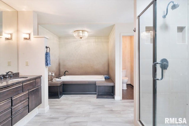 bathroom featuring a bath, a stall shower, toilet, and vanity