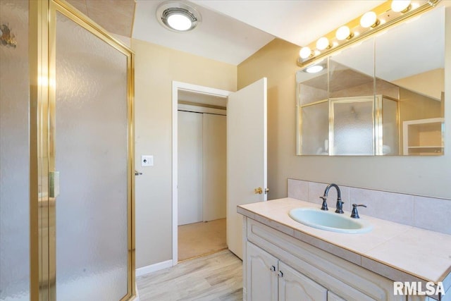 bathroom featuring wood finished floors, a stall shower, and vanity