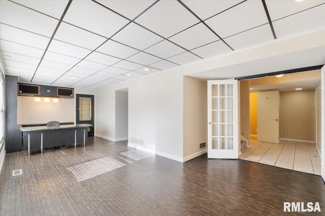 unfurnished living room featuring a drop ceiling, baseboards, and visible vents